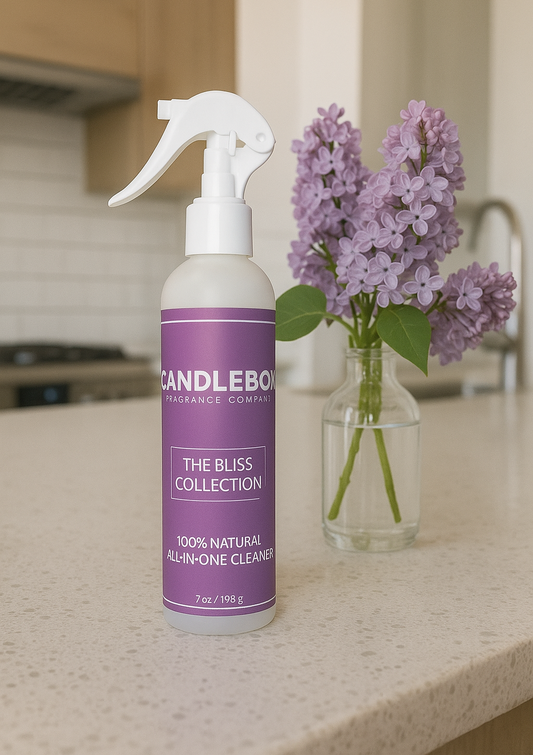 Bliss All-in-One Cleaner spray bottle with purple label on kitchen counter next to vase of lilac flowers