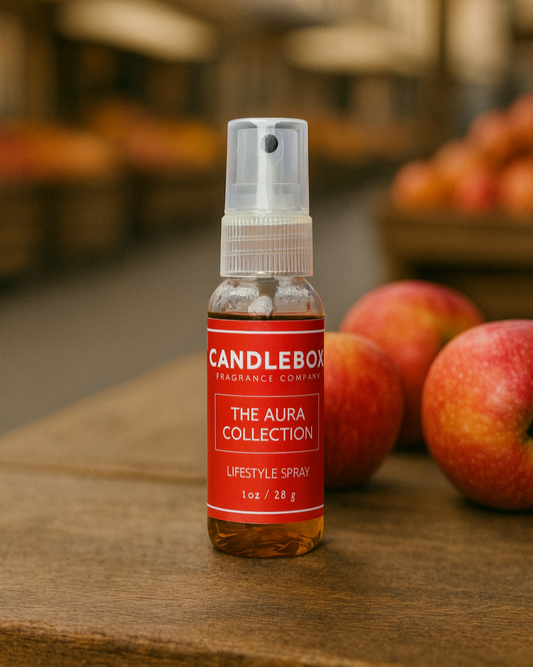 Aura Lifestyle Spray bottle from Candlebox with red label on wooden surface near apples