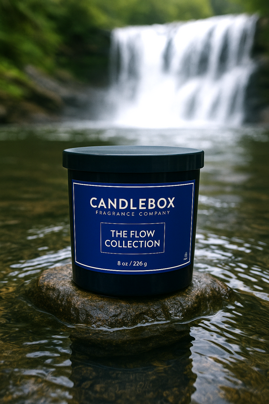 Flow Candle from The Flow Collection by Candlebox Fragrance Company placed on a rock in a river with a waterfall background