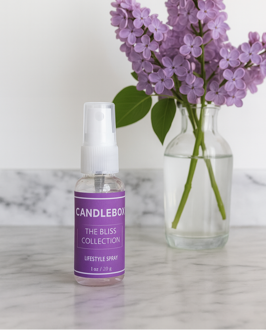 Bliss Lifestyle Spray bottle beside purple lilac flowers in glass vase on marble surface